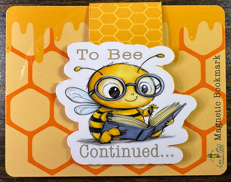 Cute magnetic bookmark with cartoon bee in glasses holding a book and the phrase “To Bee Continued…”