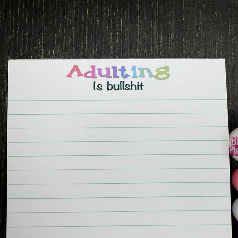 5x7 funny notepad with the phrase “Adulting Is Bullshit” at the top, lined pages, 50 sheets – part of the Notions notepad collection. Close up view of saying.