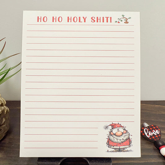 Funny Christmas 5x7 notepad with the phrase “Ho Ho Holy Shit!” in red text, lined pages, and a cute Santa illustration – humorous holiday stationery for notes and lists.