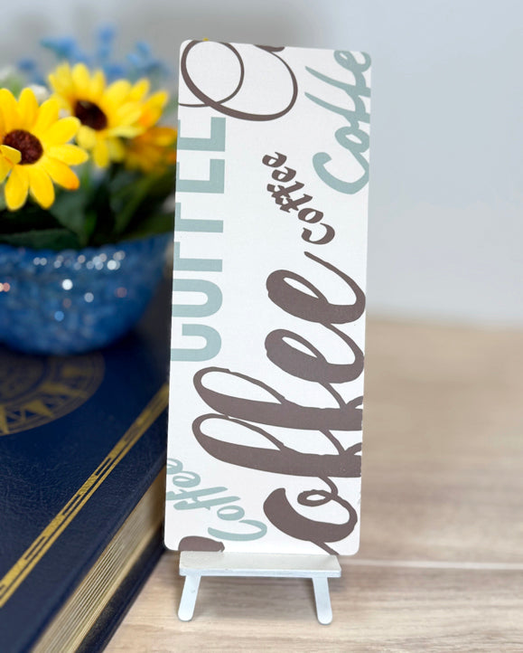 “Back of classic bookmark featuring large coffee typography in neutral brown and teal tones.”