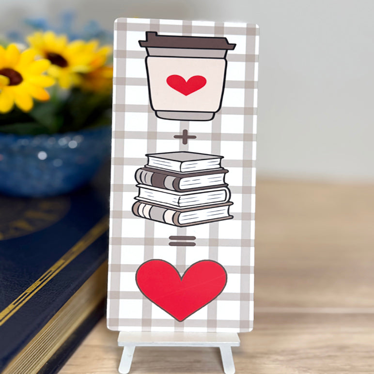 “Coffee + books = love classic bookmark displayed upright with plaid background and bold red heart design.”