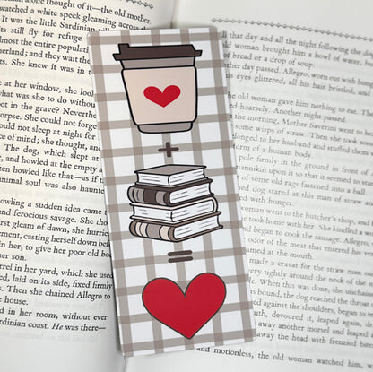 “Classic bookmark with coffee cup, books, and heart equation on a neutral plaid background placed on pages of an open book.”