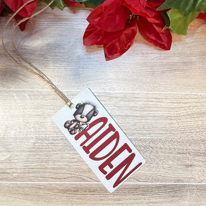 Flat lay of a personalized Christmas bag tag with the name Aiden and an adorable bear holding a candy cane.