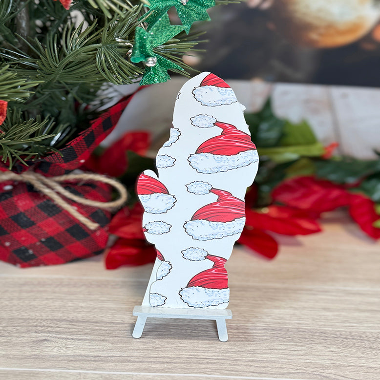 “Back of Santa classic bookmark with repeating red Santa hat pattern displayed on a small stand in front of Christmas greenery and décor.”