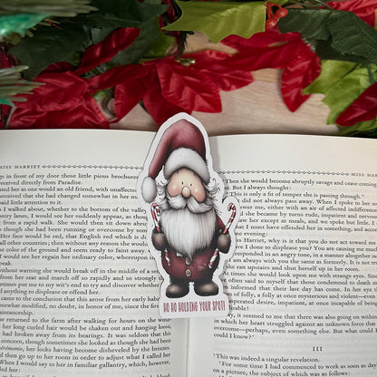 “Santa classic bookmark standing on a small easel, featuring a cute Santa holding candy canes with the phrase ‘Ho Ho Holding Your Spot!’ at the bottom.”