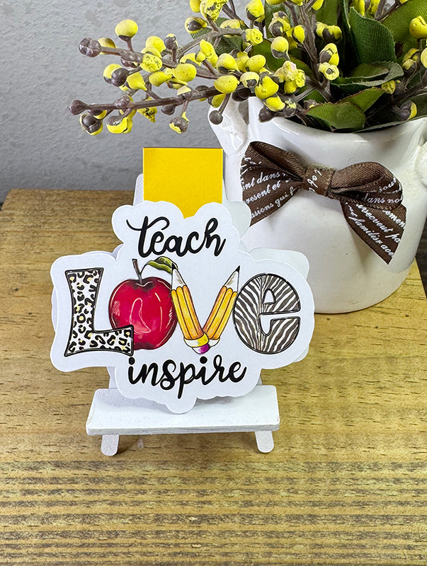 Magnetic bookmark with “Teach Love Inspire” quote, apple and pencil illustrations, and yellow tab
