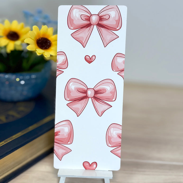 “Back of book review bookmark featuring repeating pink bow pattern on white background, displayed upright.”