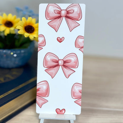 “Back of book review bookmark featuring repeating pink bow pattern on white background, displayed upright.”