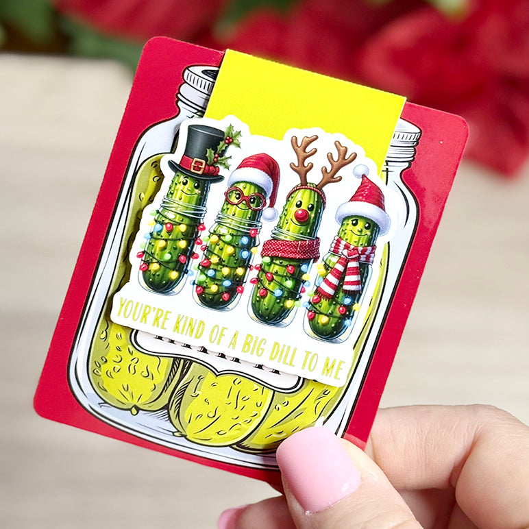 “Close-up of Christmas pickle magnetic bookmark on red backing card with holiday pickle jar design and pun quote.”
