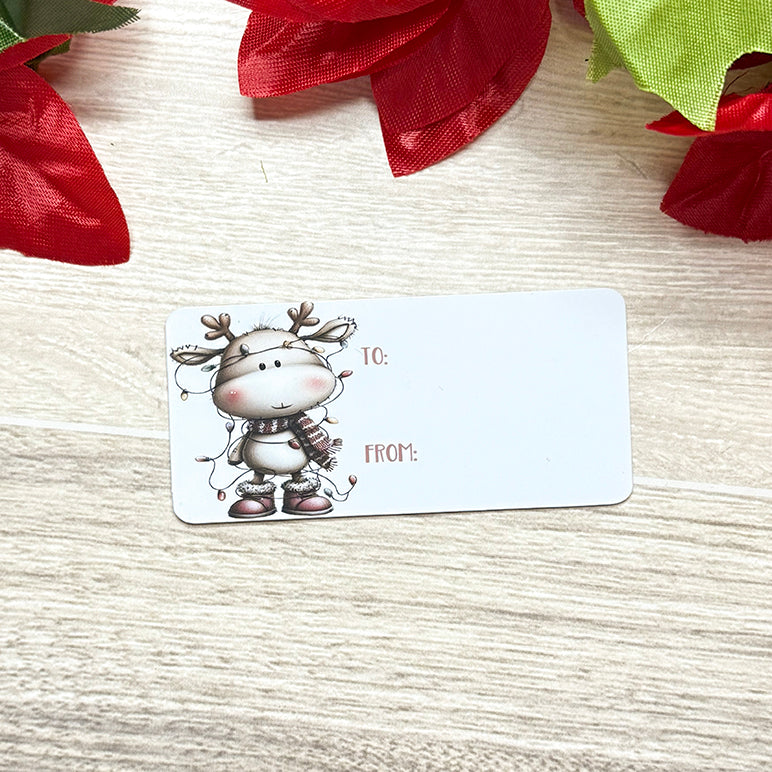 Close-up of a blank soft-touch Christmas gift tag with a cute reindeer design and “To/From” text.