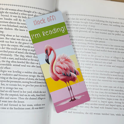 “Flamingo themed classic bookmark placed inside an open book with bright pastel stripes and humorous text ‘Flock Off I’m Reading.’”