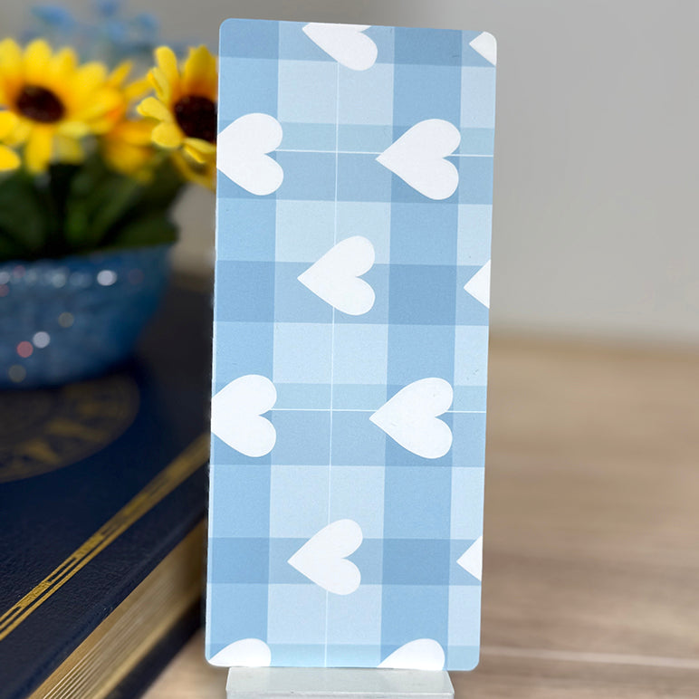“Back of classic bookmark featuring blue plaid design with white heart pattern displayed upright.”