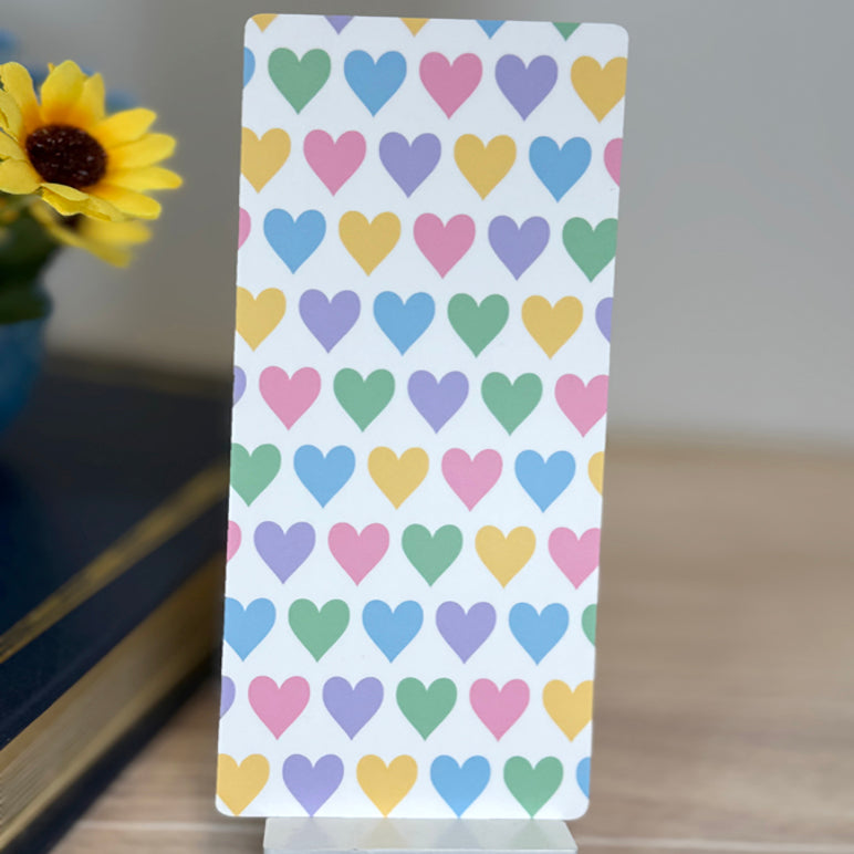 “Back of classic bookmark featuring repeating pastel heart pattern in yellow, pink, purple, green, and blue.”