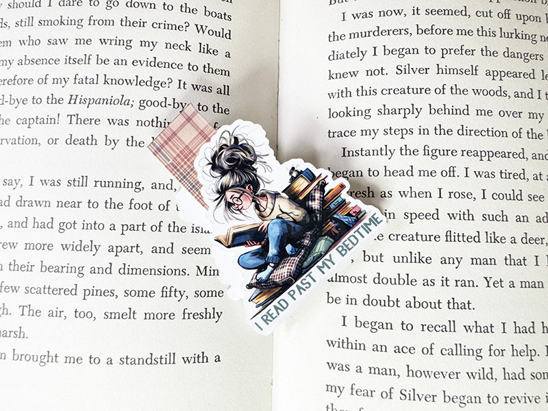 Magnetic bookmark with girl reading past bedtime, surrounded by books and pillows, with plaid tab